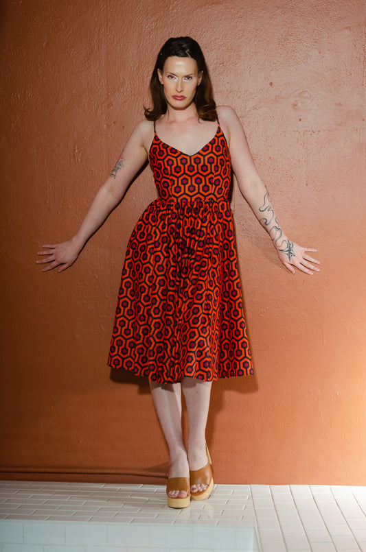 Model in the Amalie ballerina swing dress in orange and black Hotel Hexagon print, fitted bodice with adjustable spaghetti straps and a full gathered skirt