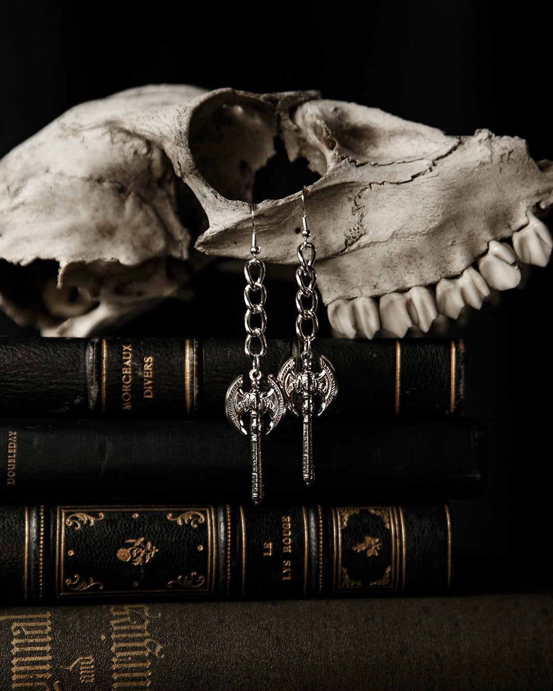 Pair of silver Beserker battle axe drop earrings laid flat, The Pretty Cult