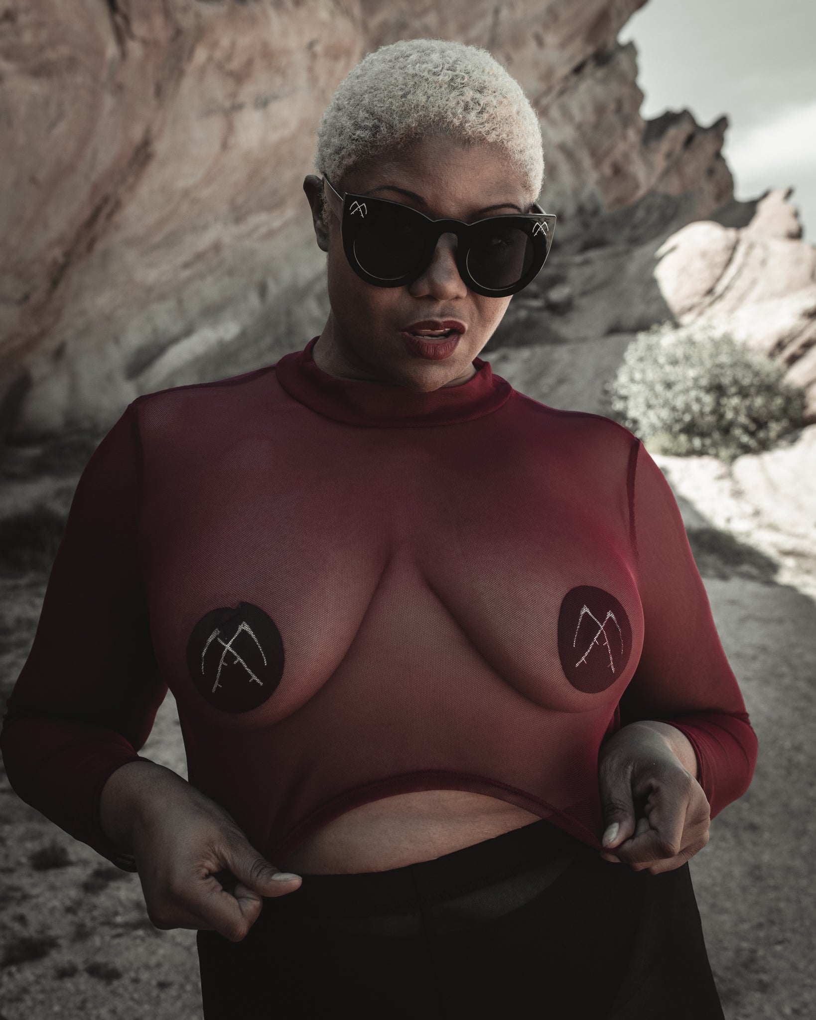 Black satin Scythe pasties worn under a sheer mesh top