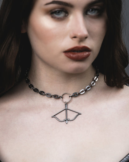 Model wearing the Aether choker in silver, a bow and arrow pendant on a dark steel chain, by The Pretty Cult