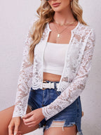 Close front view of the white lace open front jacket layered over a white crop top with denim shorts