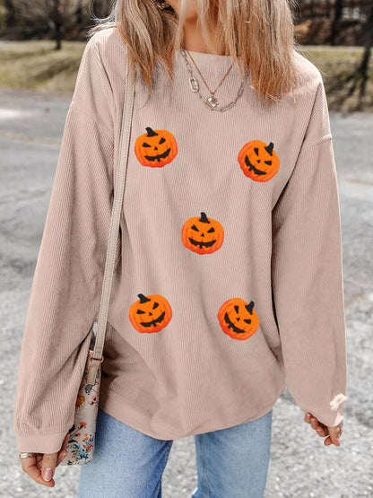 Close-up of the orange jack-o'-lantern graphics on the taupe brown sweatshirt