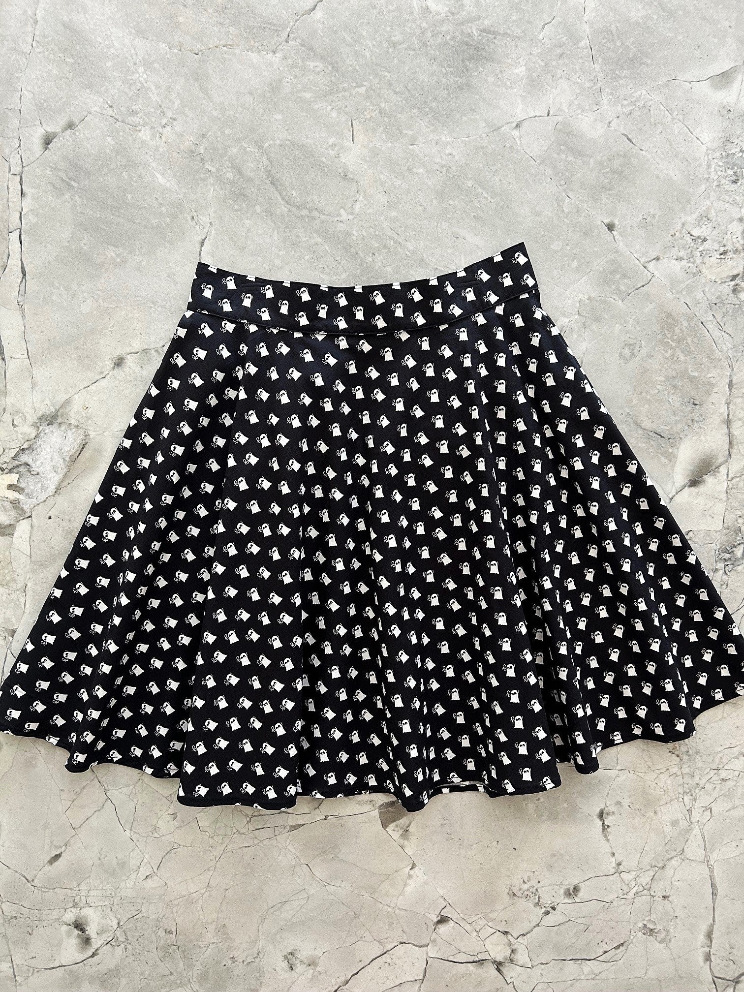 Black and white Mini Ghosts skater skirt with a white ghost print on black cotton, laid flat