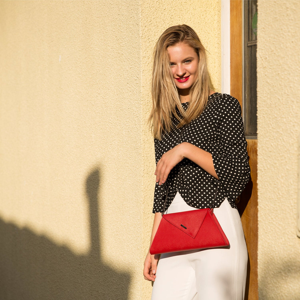 Angelica red leather clutch carried by a model, another view, by Pinup Girl Clothing