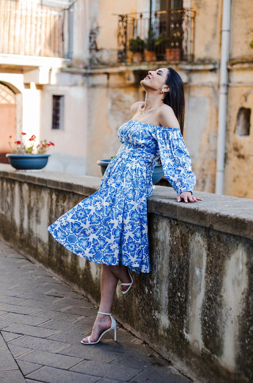 Model in the Marie-Therese peasant day dress in blue and white Noto Tile print, with a full skirt and deep pockets, by Pinup Girl Clothing
