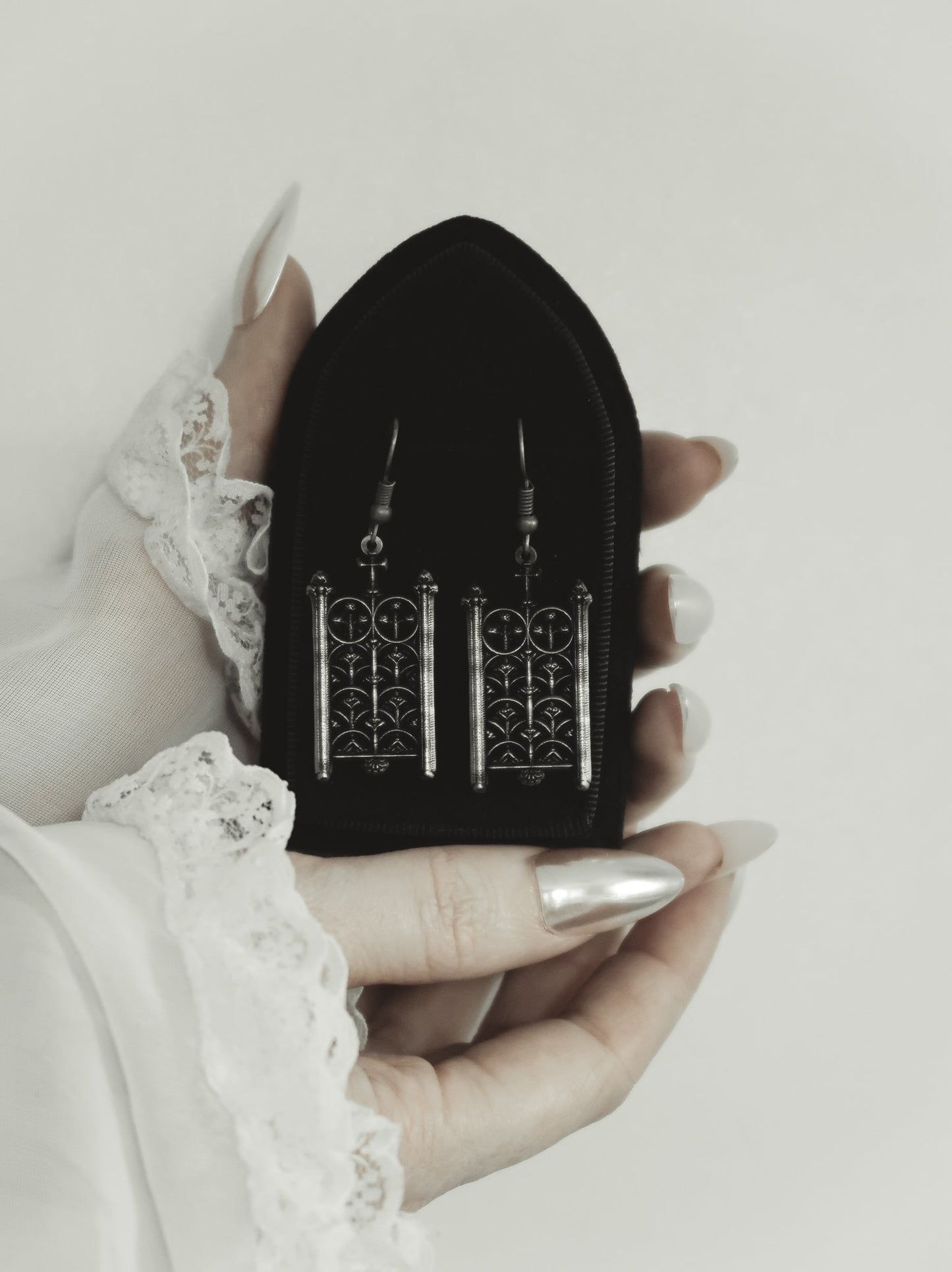 Rotunda Relic silver gate earrings resting on a black pouch, The Pretty Cult