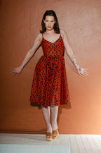 Model in the Amalie ballerina swing dress in orange and black Hotel Hexagon print, fitted bodice with adjustable spaghetti straps and a full gathered skirt