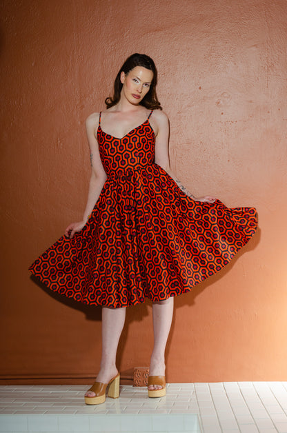 Amalie Hotel Hexagon print swing dress with the full stretch crepe skirt swept out to one side, showing the retro orange hexagon print