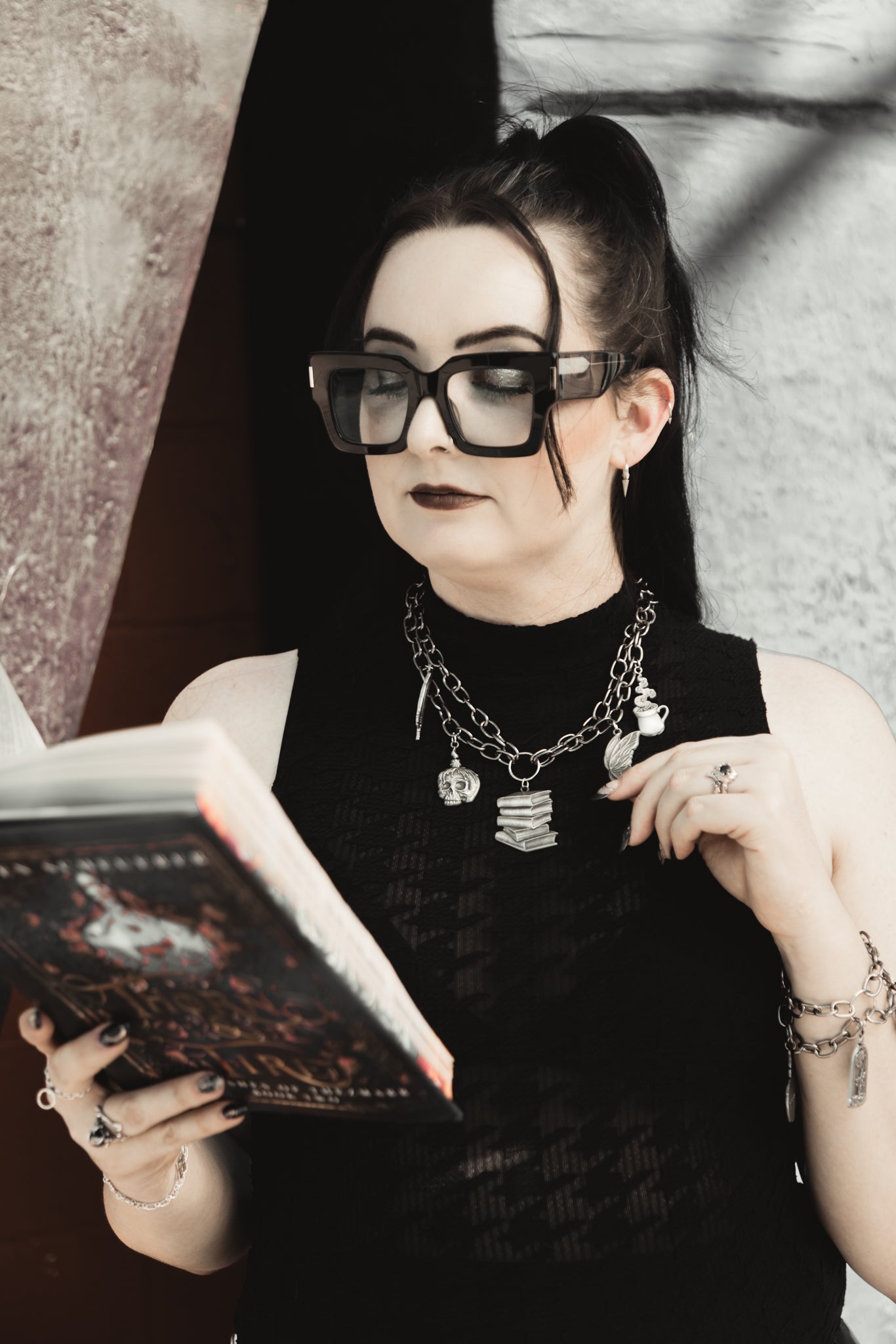 Model wearing The Night Library silver charm necklace while reading