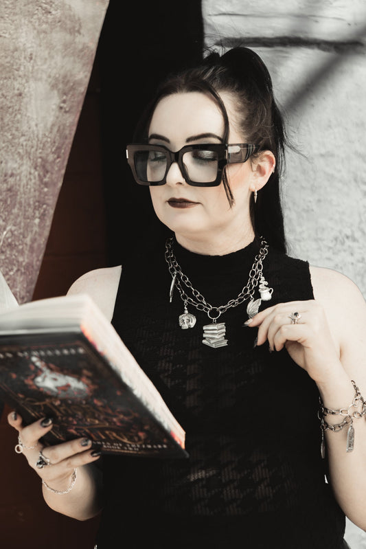 Model wearing The Night Library silver charm necklace while reading
