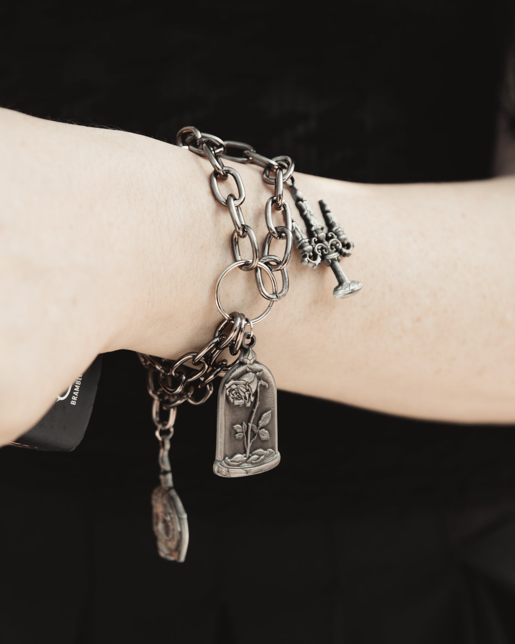 Close up of The Saint's Shadow silver charms on a delicate chain