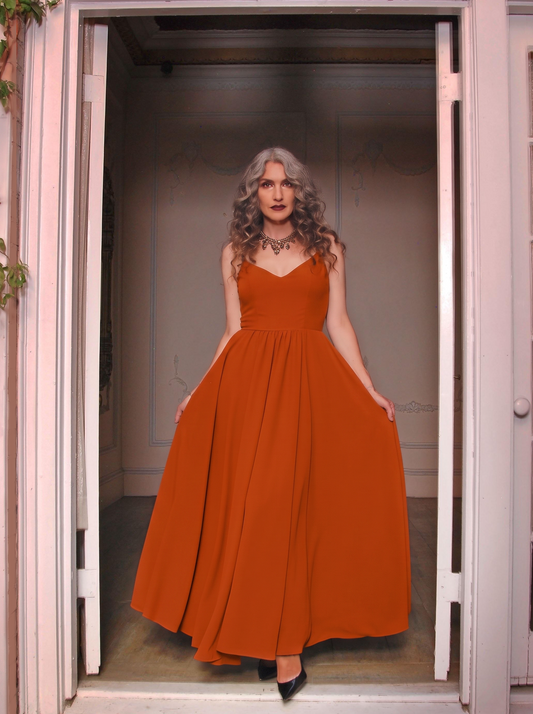 Amber Harvest Amalie maxi gown worn in a doorway, spiced orange skirt falling to the floor