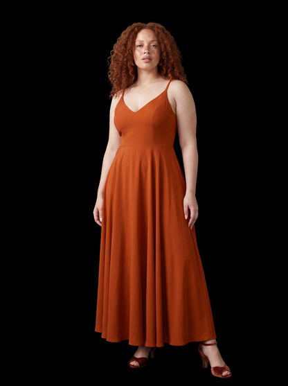 Amber Harvest Amalie maxi gown against a black backdrop, three-quarter view showing the spiced orange crepe and full skirt