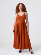 Model wearing the Amalie Ballerina maxi gown in Amber Harvest, a deep spiced orange with a fitted 70s ballerina bodice and gathered floor-length skirt