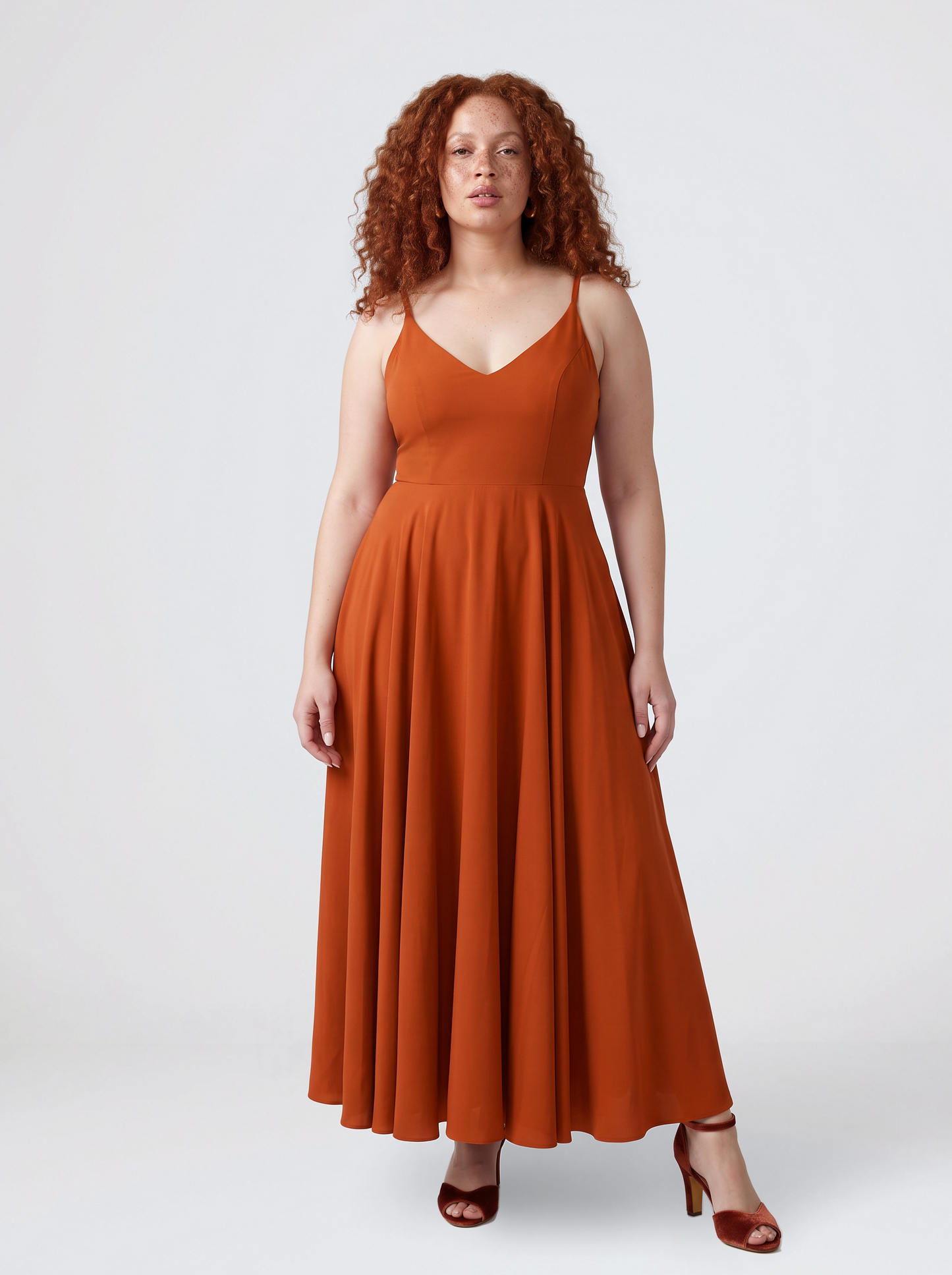 Model wearing the Amalie Ballerina maxi gown in Amber Harvest, a deep spiced orange with a fitted 70s ballerina bodice and gathered floor-length skirt