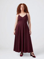 Model wearing the Amalie Ballerina maxi gown in burgundy, fitted 70s ballerina bodice with spaghetti straps and a gathered floor-length skirt