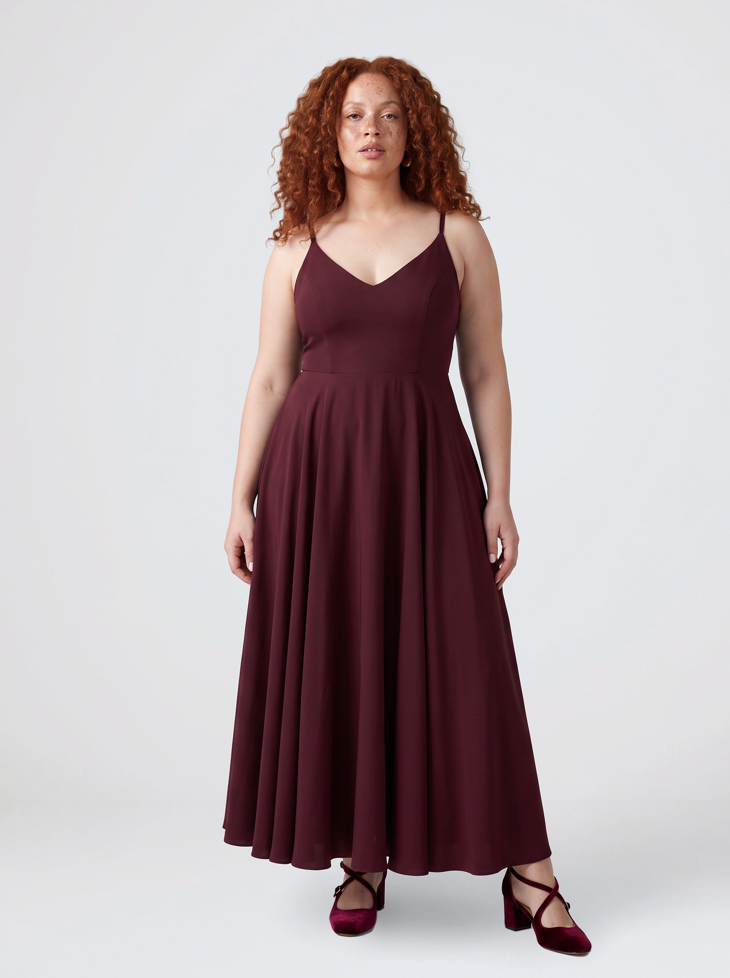 Model wearing the Amalie Ballerina maxi gown in burgundy, fitted 70s ballerina bodice with spaghetti straps and a gathered floor-length skirt