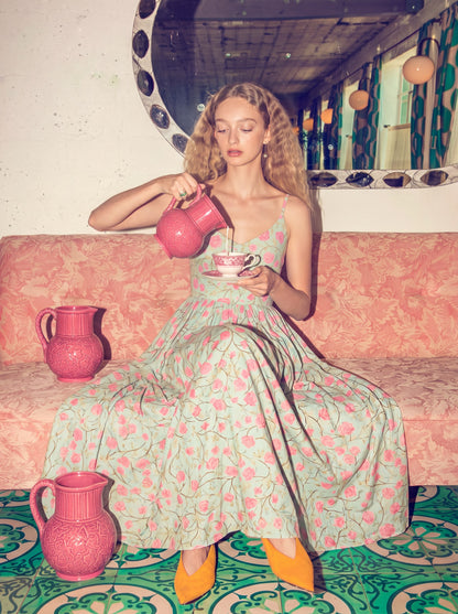 Model in the Amalie Maxi Dress in Rose Silhouette Mint, a 70s-inspired mint maxi with a pink rose print, spaghetti straps and a full gathered skirt