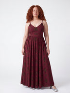 Model in the Amalie Ballerina Daytime Maxi Gown in Goth Grand Trianon, front view, black scrollwork on burgundy with a fitted ballerina bodice and spaghetti straps