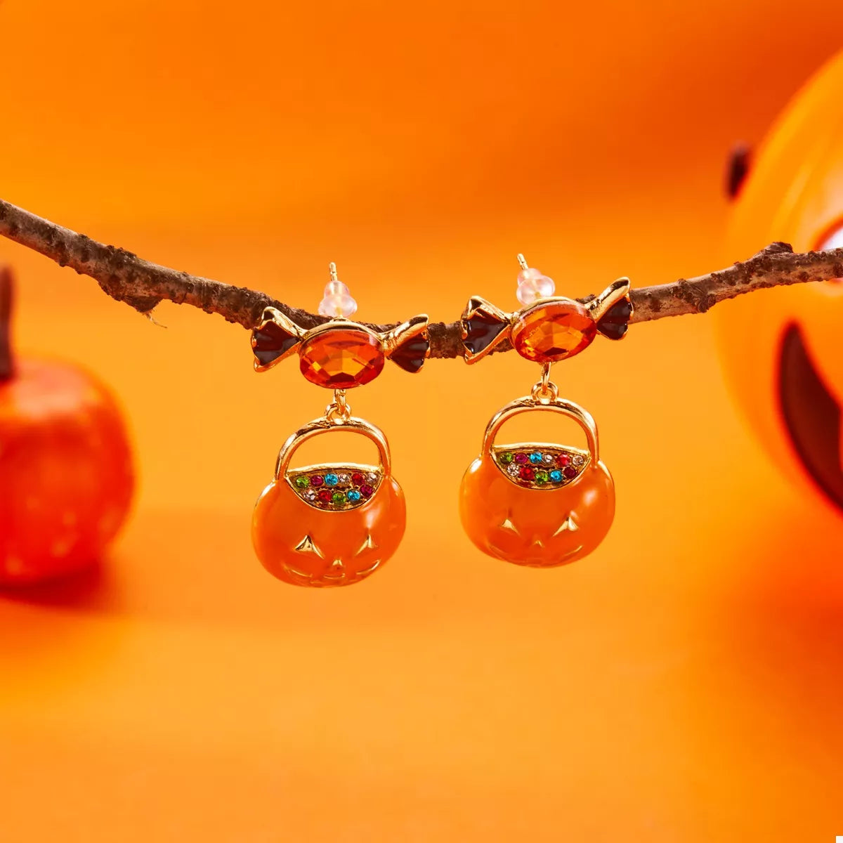 Gold-plated pumpkin drop earrings shown on the ear