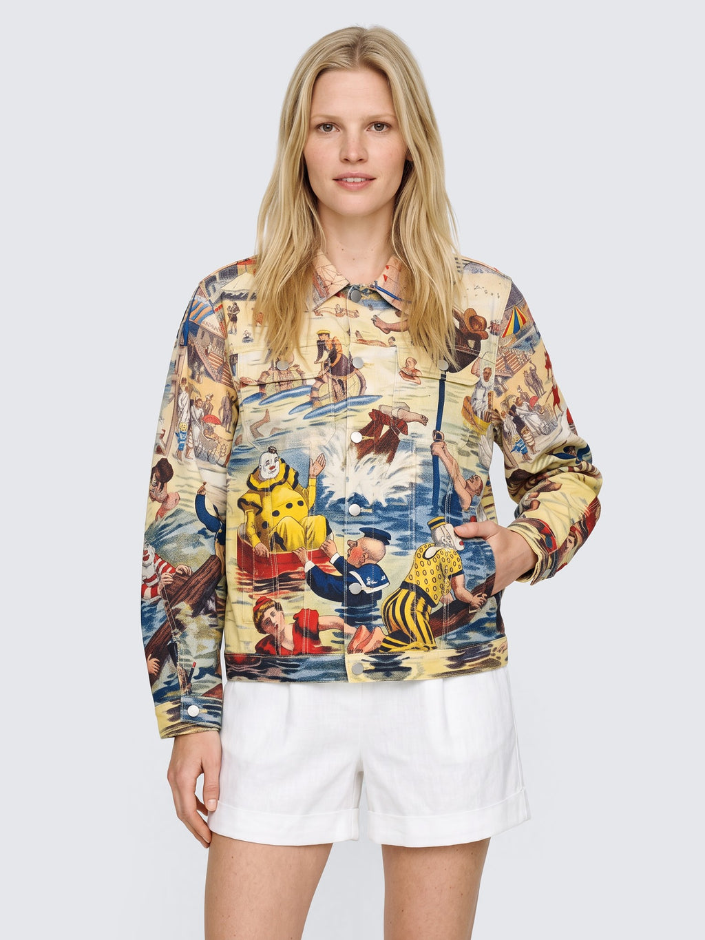 Model with one hand in the pocket of the oversized Bathing Clown Denim Jacket, buttoned, worn with white high-waisted shorts