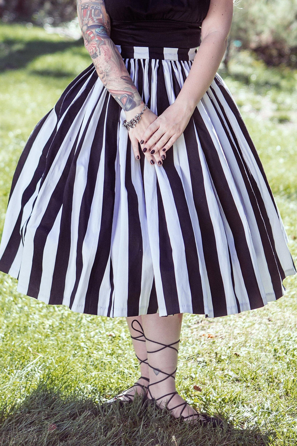 Waist-down view of the Bella swing skirt in black and white Mark Stripe sateen with lace-up sandals