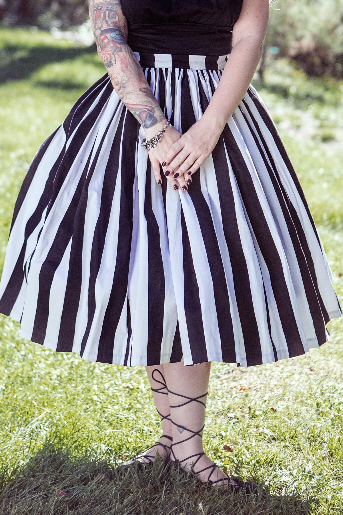 Waist-down view of the Bella swing skirt in black and white Mark Stripe sateen with lace-up sandals