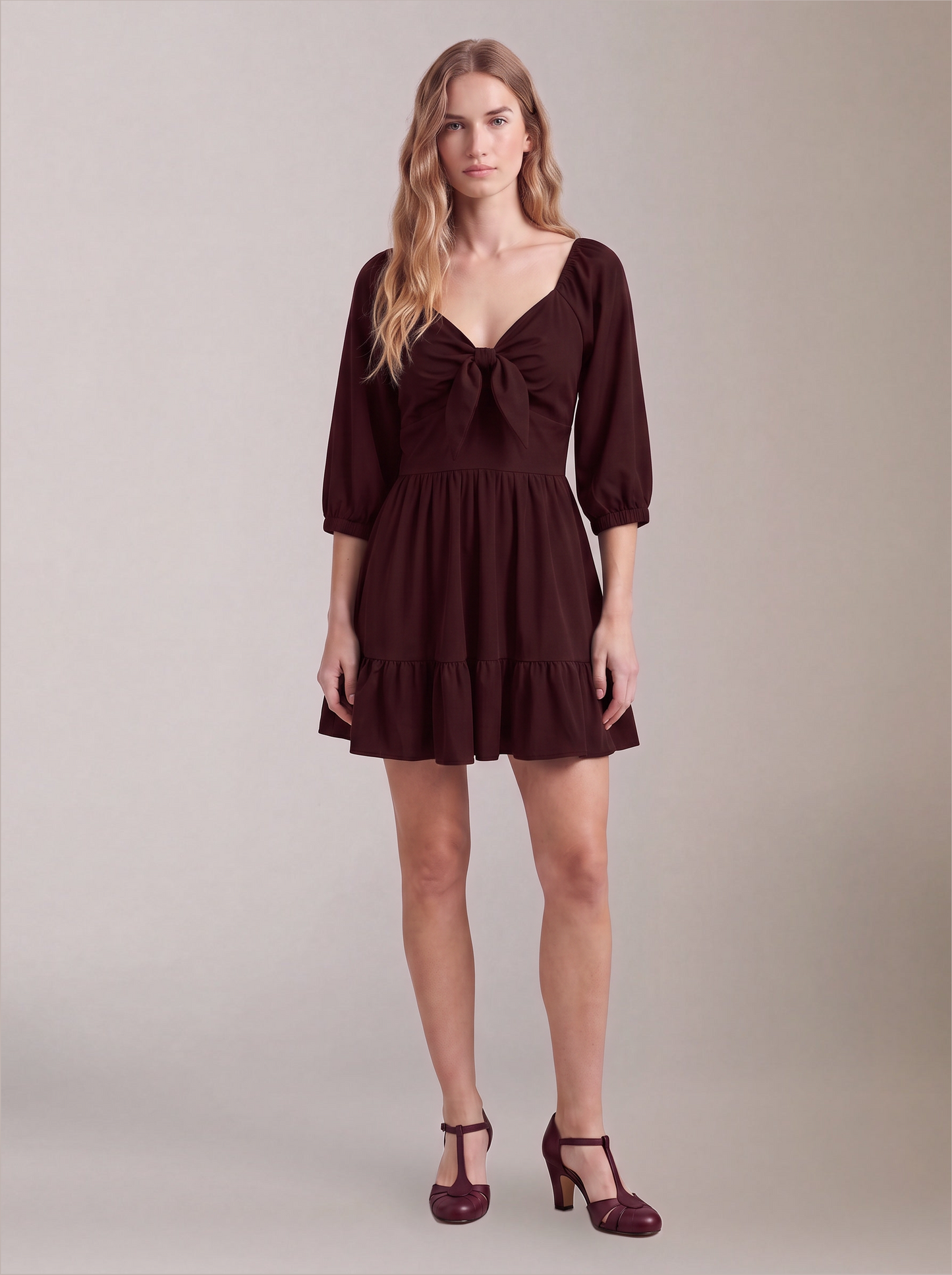 Model wearing the Molly Mini dress in solid burgundy, front view, with tie-front bodice and tiered ruffle hem skirt.