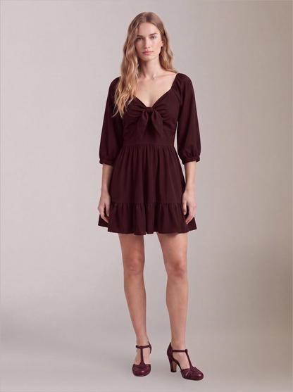 Model wearing the Molly Mini dress in solid burgundy, front view, with tie-front bodice and tiered ruffle hem skirt.