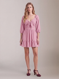 Model wearing the Molly Mini dress in Pinup Girl Pink, front view, with tie-front bodice and tiered ruffle hem skirt.
