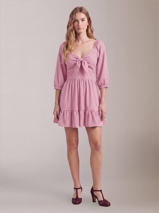 Model wearing the Molly Mini dress in Pinup Girl Pink, front view, with tie-front bodice and tiered ruffle hem skirt.