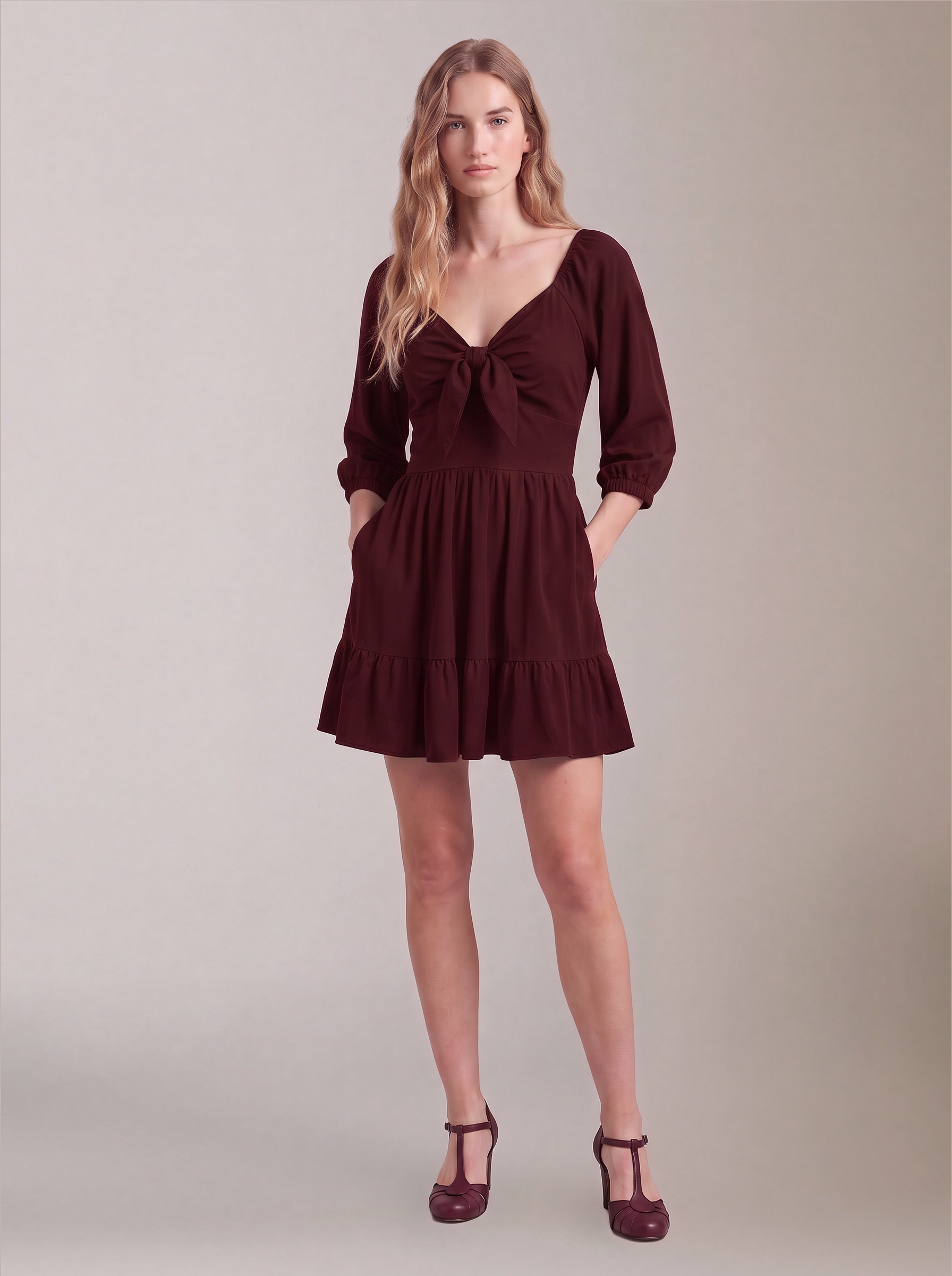 Molly Mini dress in burgundy worn with hands in the deep-set skirt pockets, by Pinup Girl Clothing.
