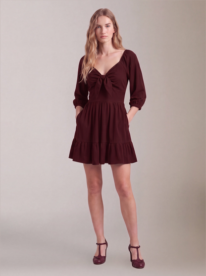 Molly Mini dress in burgundy worn with hands in the deep-set skirt pockets, by Pinup Girl Clothing.