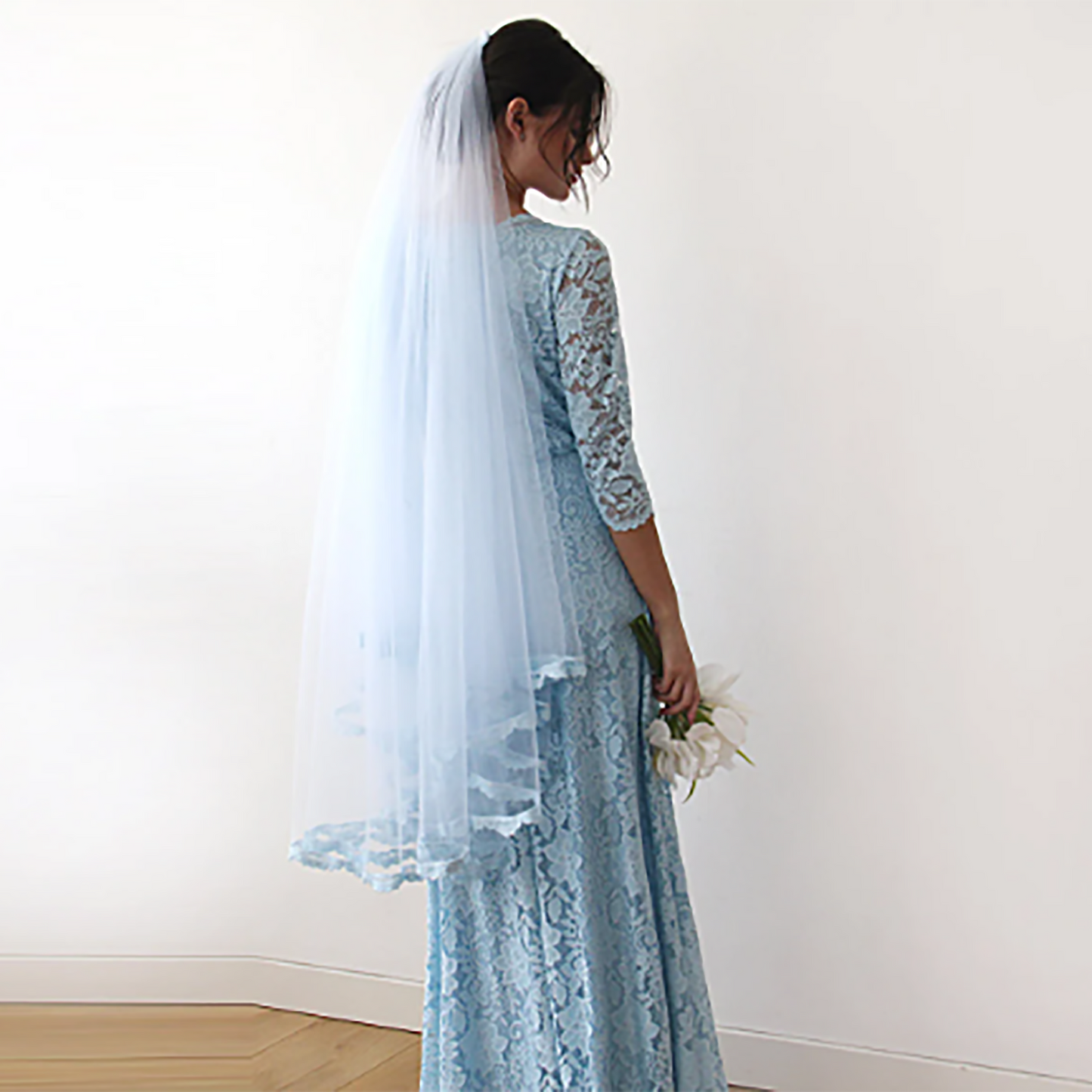 Light blue tulle bridal veil with lace trim shown on the model