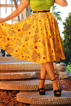 Waist-down view of the Doris swing skirt in the mustard Spanish fans print, held out to show the full sweep, with black heels