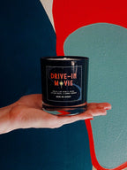 Drive-In Movie candle held in hand against a colorful mural