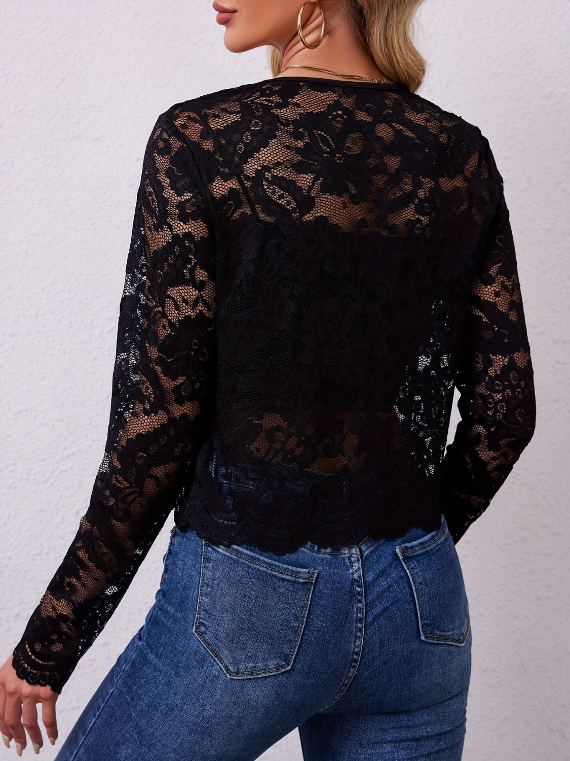 Back view of the black sheer lace open front jacket, showing the scalloped hem over jeans