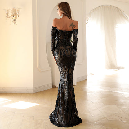 Woman in a black evening gown standing in a elegant room with mirrors.
