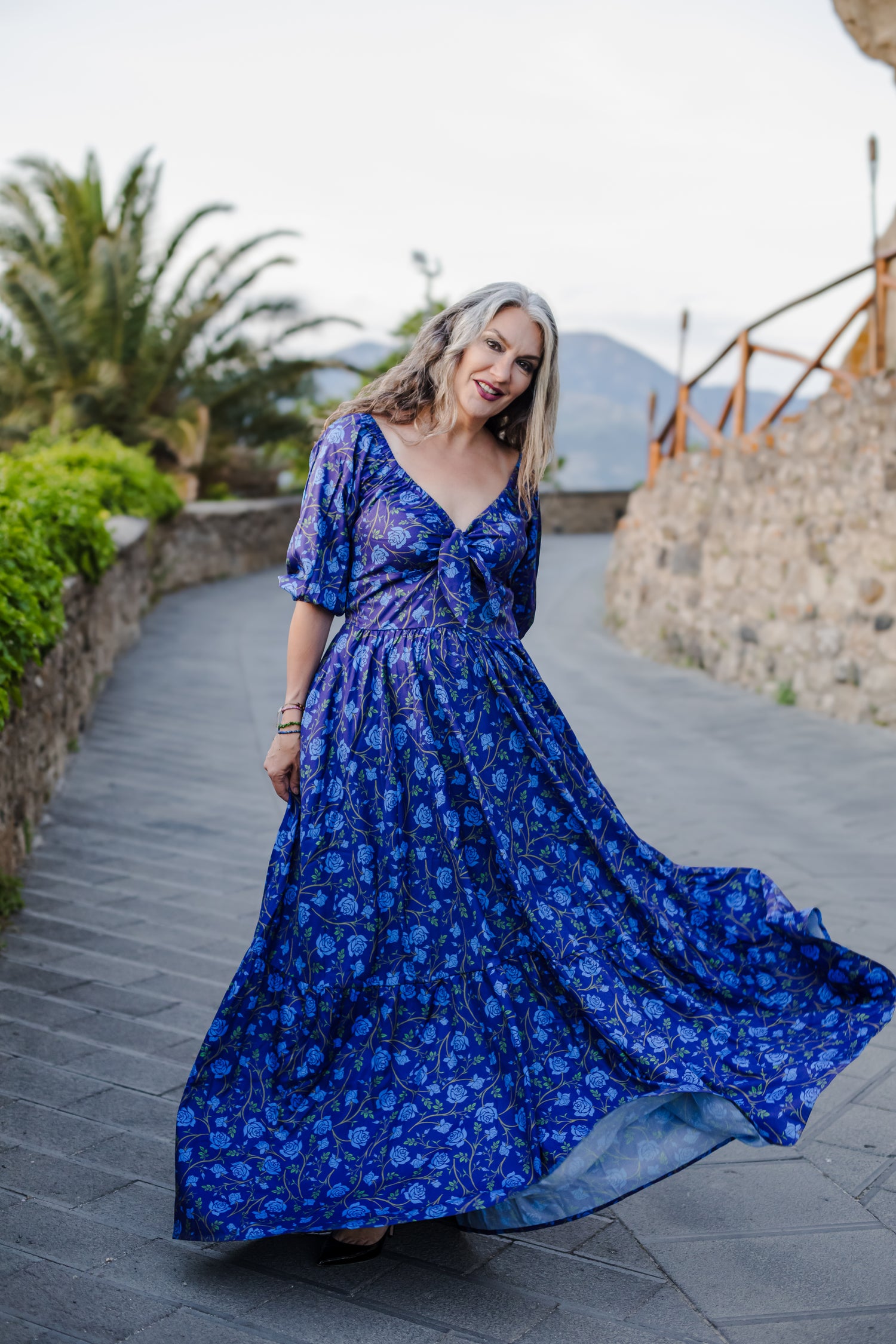 Model in the Molly Maxi dress in blue Rose Silhouette floral, with a gathered bodice and tiered skirt, by Pinup Girl Clothing