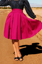 Waist-down view of the Long Jun box pleat skirt in Baton Rouge sateen, held out to show the pleats, with black sandals