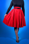 Waist-down view of the Long Jun box pleat skirt in red twill with a black belt and black heels
