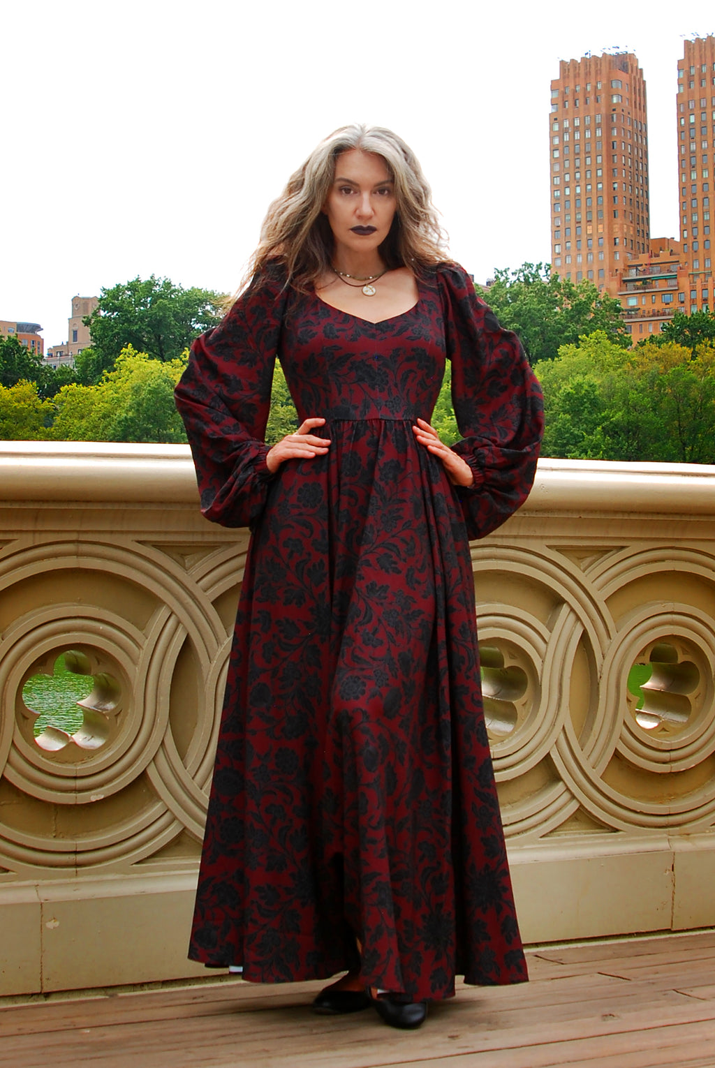 Front view of the Lucrezia renaissance maxi gown in black on red Capri Floral, the print reading deep wine red in the shade, bishop sleeves and a floor-length gathered skirt
