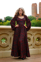 Front view of the Lucrezia renaissance maxi gown in black on red Capri Floral, the print reading deep wine red in the shade, bishop sleeves and a floor-length gathered skirt