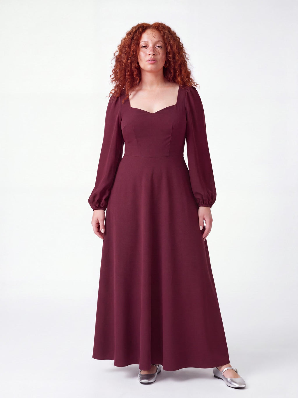 Model wearing the Lucrezia Renaissance Maxi Gown in Burgundy, front view, with a deep sweetheart neckline, long bishop sleeves and a gathered circle skirt that grazes the floor