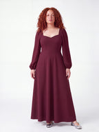 Model wearing the Lucrezia Renaissance Maxi Gown in Burgundy, front view, with a deep sweetheart neckline, long bishop sleeves and a gathered circle skirt that grazes the floor