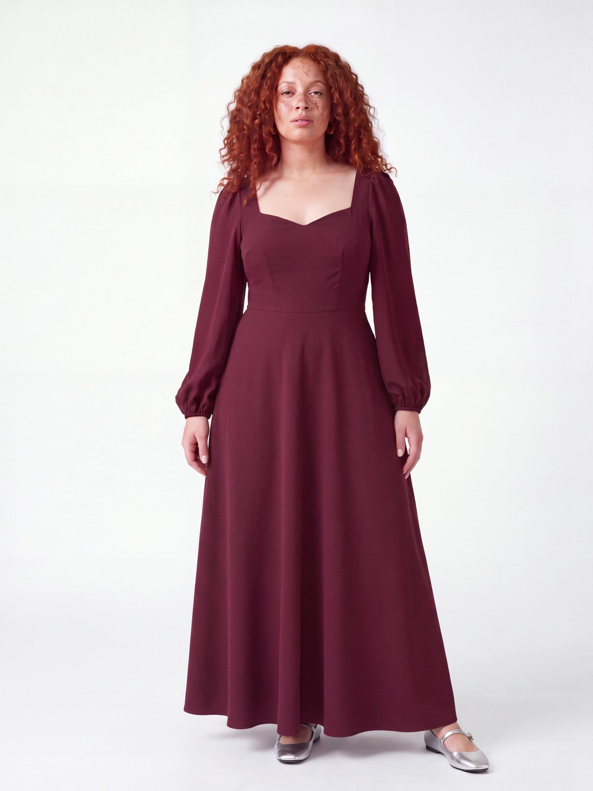 Model wearing the Lucrezia Renaissance Maxi Gown in Burgundy, front view, with a deep sweetheart neckline, long bishop sleeves and a gathered circle skirt that grazes the floor