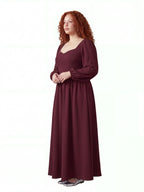Model in the burgundy Lucrezia renaissance maxi gown, three-quarter view, showing the fitted bodice, cuffed bishop sleeves and the full floor-length skirt