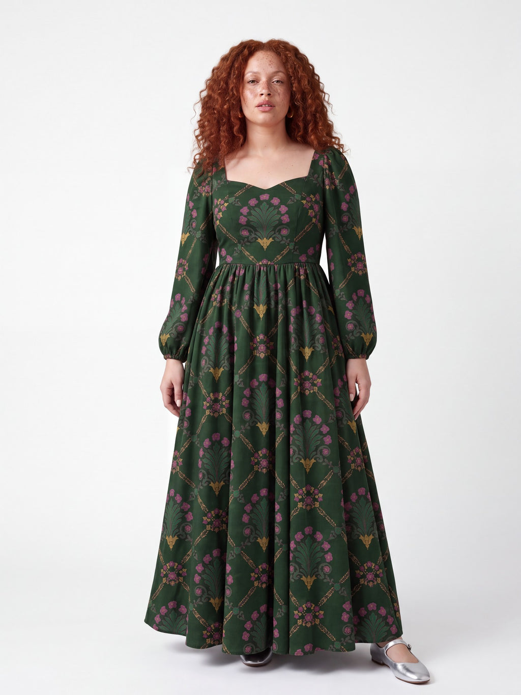 Model in the Lucrezia Renaissance Maxi Gown in Dark Green Grand Trianon, front view, pink blooms and gold scrolls on forest green with bishop sleeves and a floor-grazing skirt