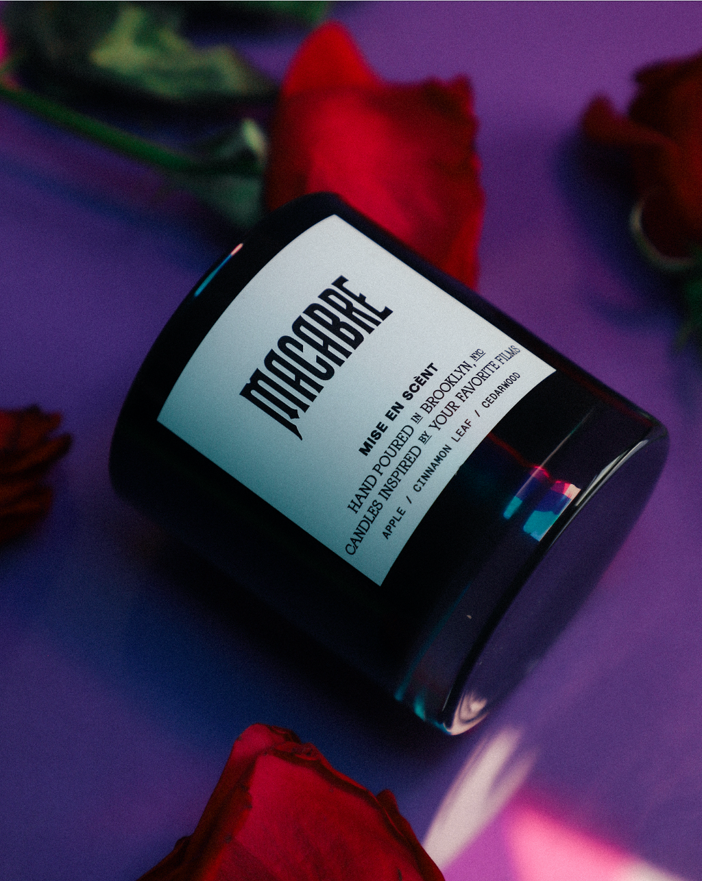 Macabre candle lying on purple with red rose petals
