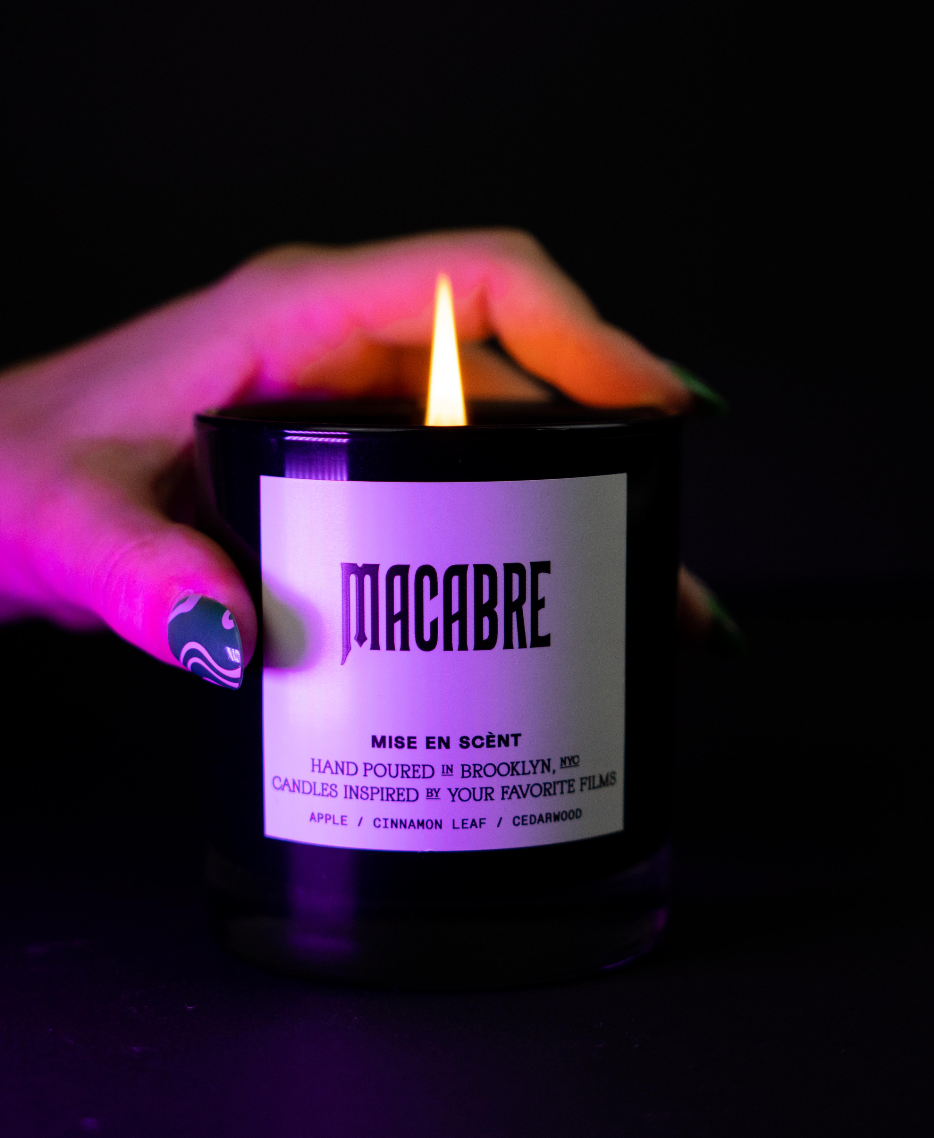 Macabre candle lit and held in hand under purple light